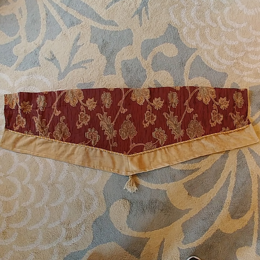 Burgandy and gold valance with decorative tassel.